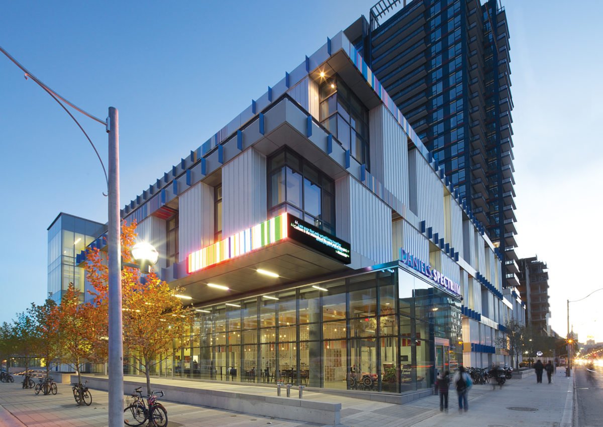 Daniels Spectrum exterior at dusk — colorful modern façade with glass entrance